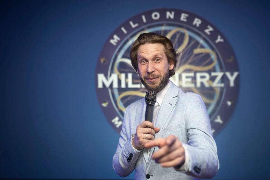 konferansjer mówi przez mikrofon na teleturnieju firmowym
